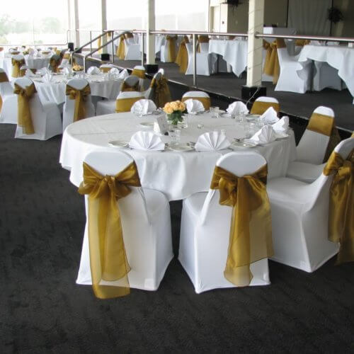White chair covers with antique gold sashes.